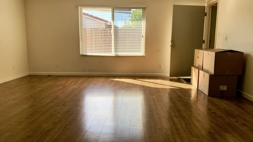 An empty living room on move-out day, freshly mopped floor and boxes stacked by the door